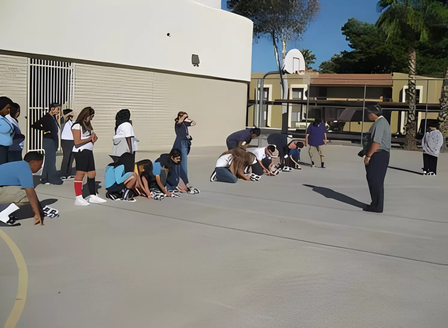 Students kneeling outdoors, listening to instructor.